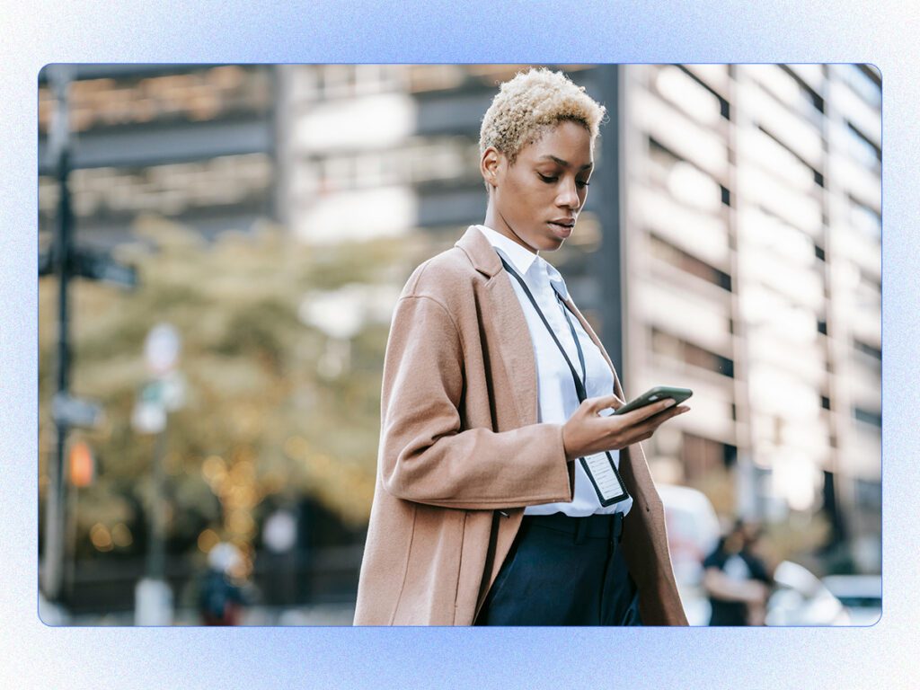 A stylized stock photo of a professional woman outside using her phone. 